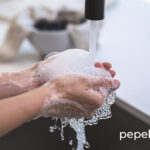 manos lavándose con agua y jabón con el grifo abierto