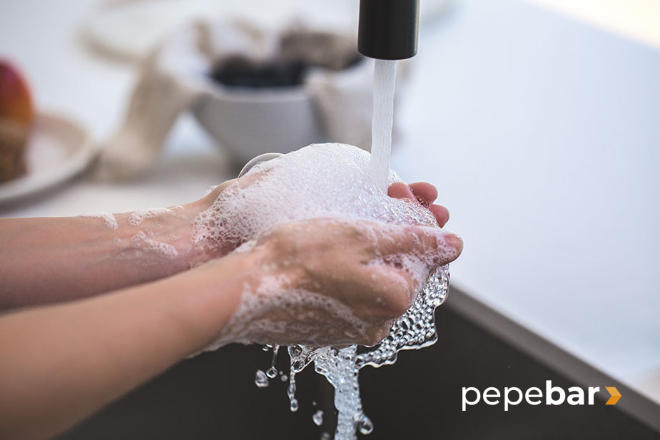 manos lavándose con agua y jabón con el grifo abierto