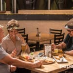tres personas mayores riéndose y tomando algo en un bar